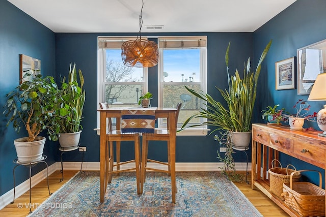 living area featuring visible vents, baseboards, and wood finished floors