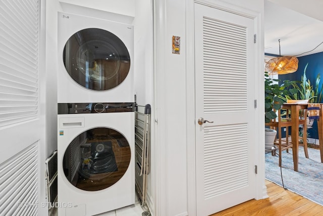 laundry area with laundry area, stacked washer / drying machine, and wood finished floors