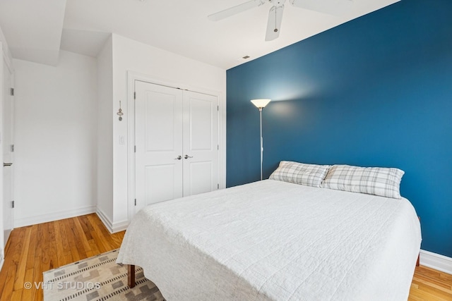 bedroom with a closet, ceiling fan, baseboards, and wood finished floors