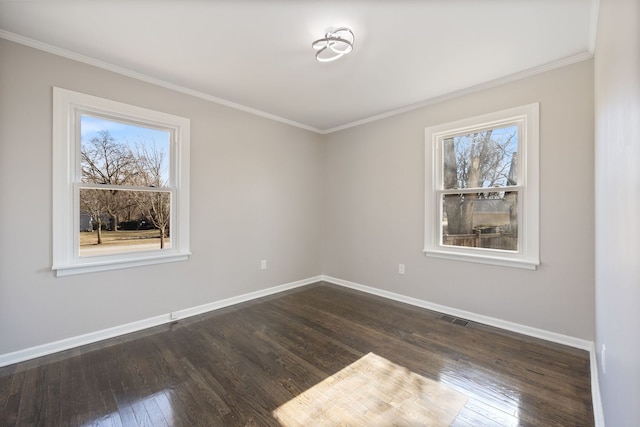 spare room featuring crown molding, dark wood finished floors, visible vents, and baseboards