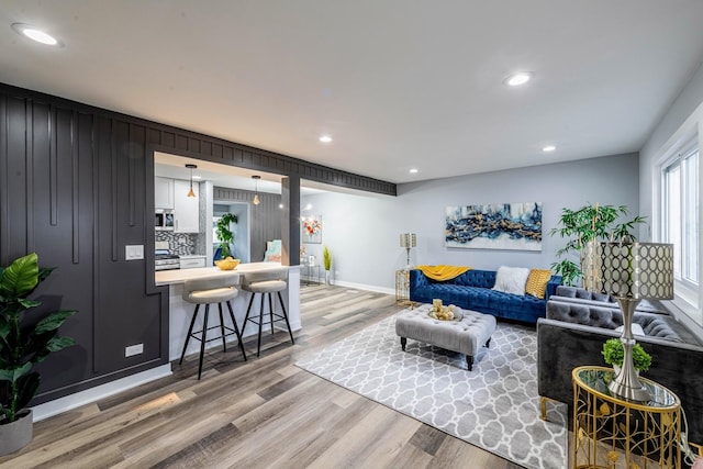 living room with light wood-style floors, recessed lighting, and baseboards