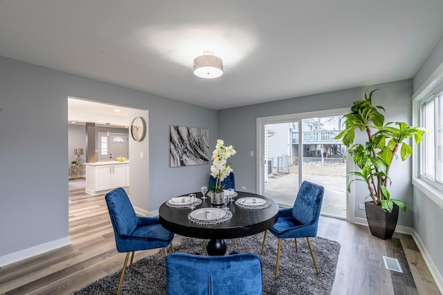 dining area with light wood-style floors, visible vents, and baseboards