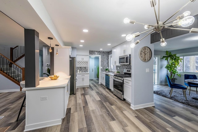 kitchen featuring light countertops, appliances with stainless steel finishes, white cabinetry, and tasteful backsplash