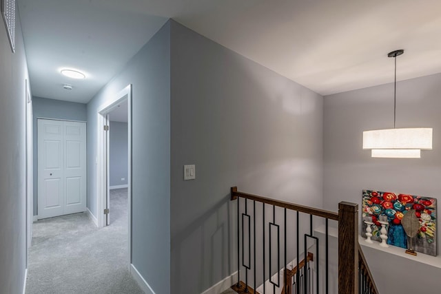 corridor featuring carpet floors, baseboards, and an upstairs landing