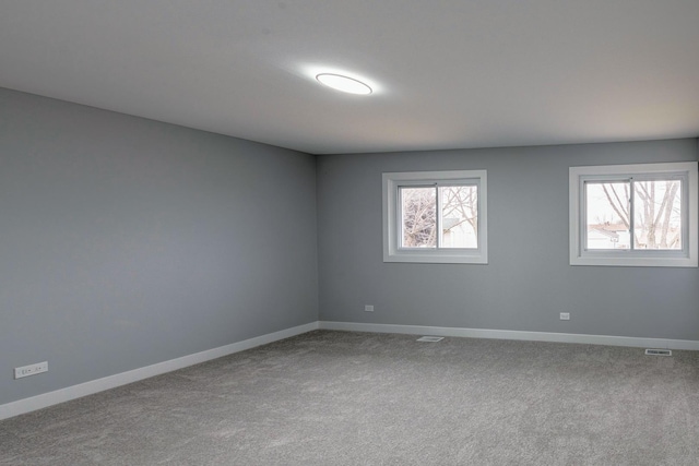 unfurnished room featuring plenty of natural light, visible vents, and baseboards