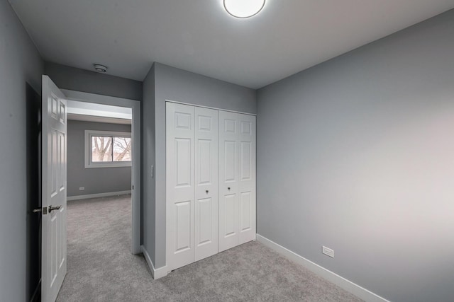 unfurnished bedroom with a closet, carpet flooring, and baseboards