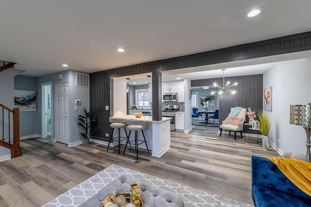 kitchen featuring appliances with stainless steel finishes, light wood-style flooring, white cabinets, and a notable chandelier