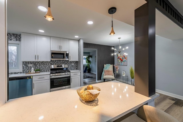 kitchen featuring tasteful backsplash, wood finished floors, hanging light fixtures, stainless steel appliances, and recessed lighting