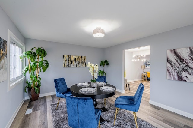 dining area with baseboards, a chandelier, and wood finished floors