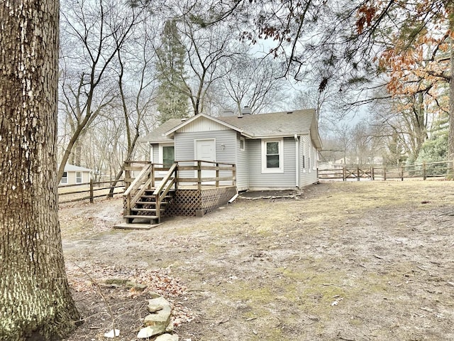 view of front facade with a shingled roof, fence, and a deck