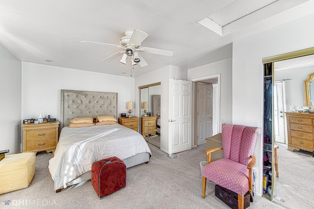 bedroom with ceiling fan, attic access, two closets, and carpet flooring