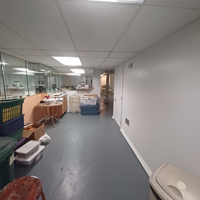 finished basement featuring a paneled ceiling, baseboards, and visible vents