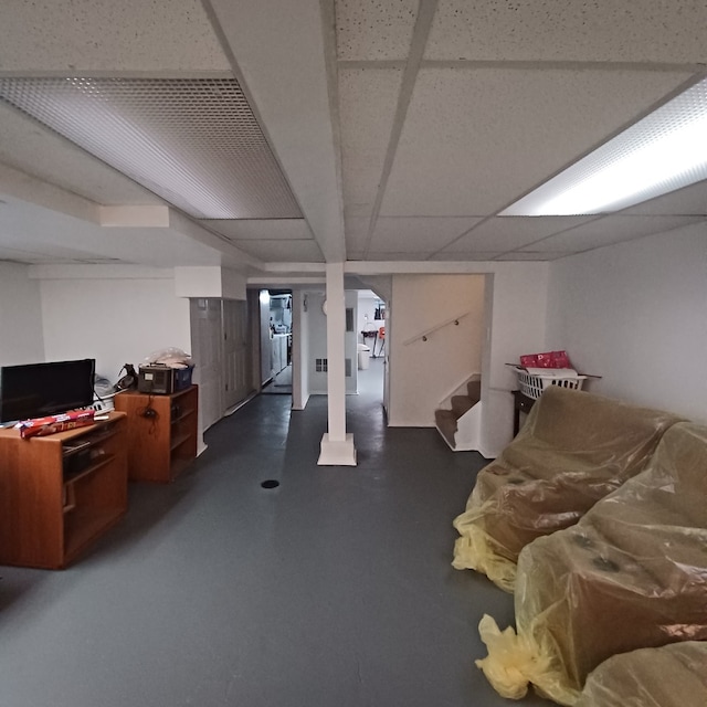 finished basement featuring a paneled ceiling and stairs