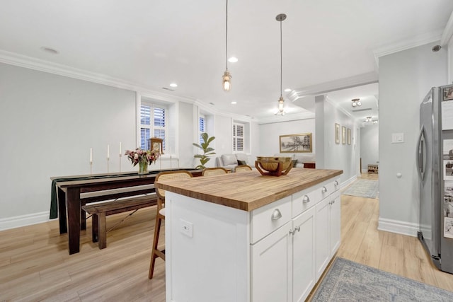 kitchen with wooden counters, light wood-style flooring, crown molding, and freestanding refrigerator