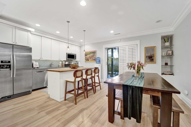 kitchen with a breakfast bar, a sink, tasteful backsplash, stainless steel appliances, and crown molding