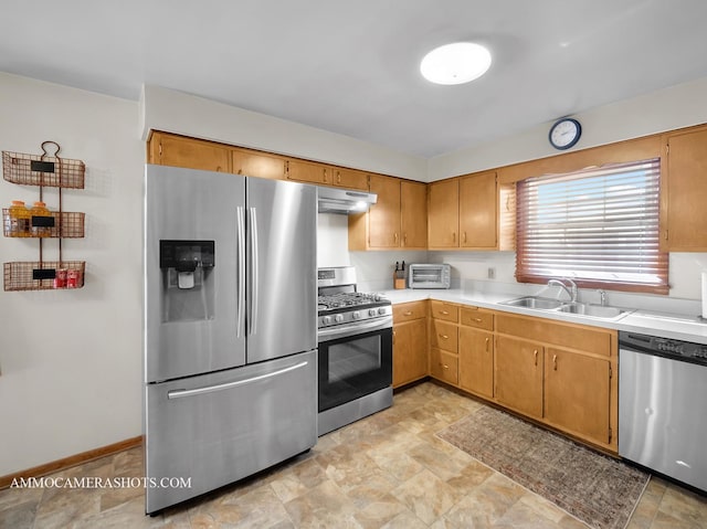 kitchen with a toaster, stainless steel appliances, light countertops, under cabinet range hood, and a sink