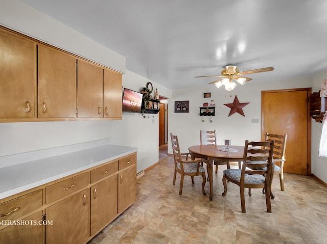 dining space featuring ceiling fan, stone finish floor, and baseboards