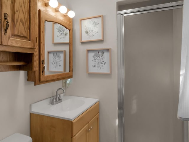 bathroom with toilet, a stall shower, and vanity