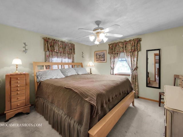 bedroom with light colored carpet, ceiling fan, and baseboards