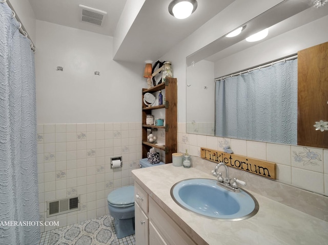 bathroom with toilet, visible vents, tile walls, and vanity