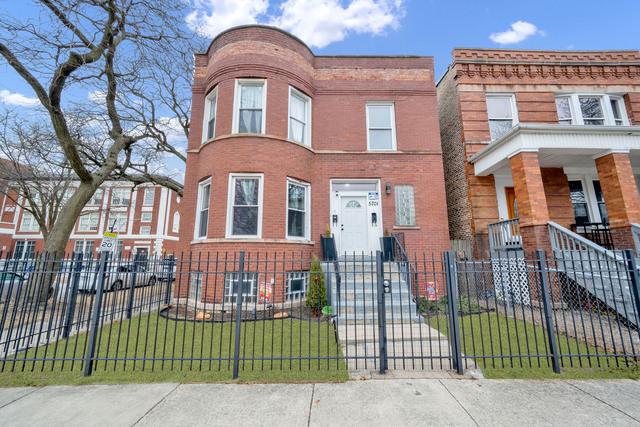 multi unit property featuring brick siding, a fenced front yard, a front yard, and a gate