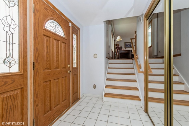 foyer entrance with light tile patterned floors, baseboards, and stairs