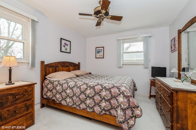 bedroom with a ceiling fan, light carpet, and baseboards