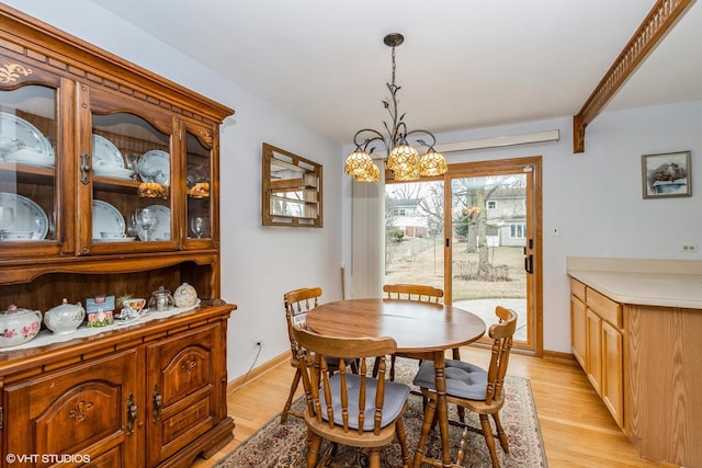 dining space featuring baseboards, light wood finished floors, and an inviting chandelier