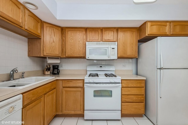 kitchen with white appliances, a sink, light countertops, backsplash, and light tile patterned flooring