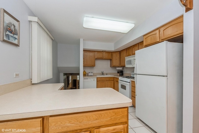 kitchen featuring white appliances, light tile patterned floors, a peninsula, light countertops, and a sink