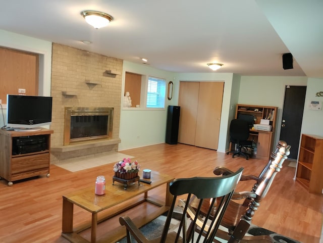 living area featuring light wood-type flooring, a fireplace, and baseboards