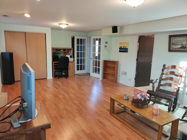 living area featuring light wood-type flooring, visible vents, and french doors