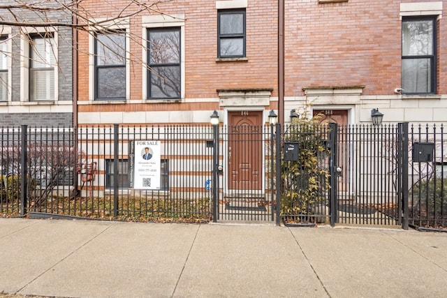 view of front of home featuring a fenced front yard, a gate, and brick siding