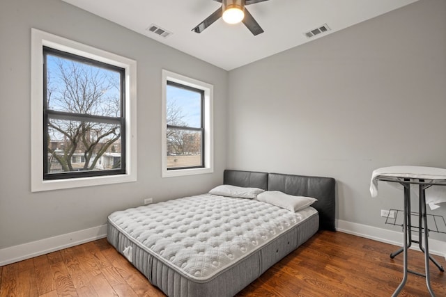 bedroom with a ceiling fan, baseboards, visible vents, and wood finished floors