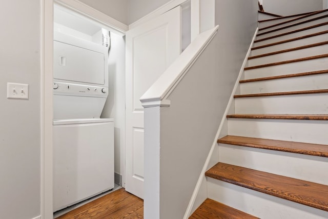 stairway with wood finished floors and stacked washer and clothes dryer