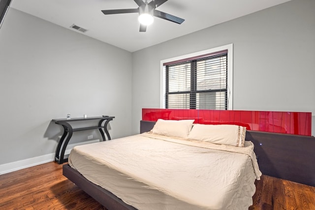 bedroom featuring baseboards, visible vents, ceiling fan, and wood finished floors