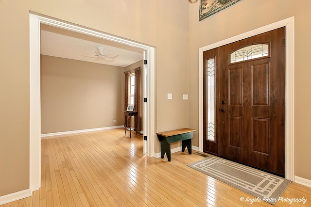 foyer entrance featuring light wood-style floors, baseboards, and a ceiling fan