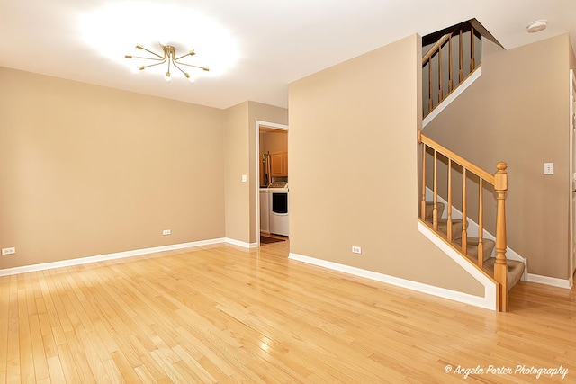 unfurnished living room featuring light wood-type flooring, baseboards, stairway, and washer / clothes dryer