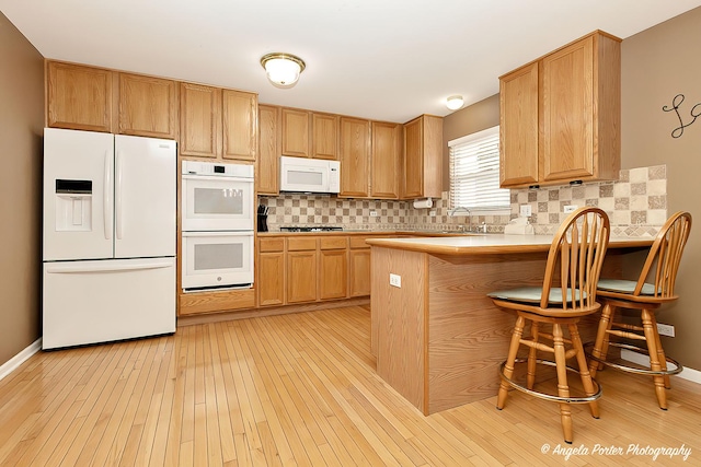 kitchen with white appliances, decorative backsplash, light wood finished floors, and light countertops