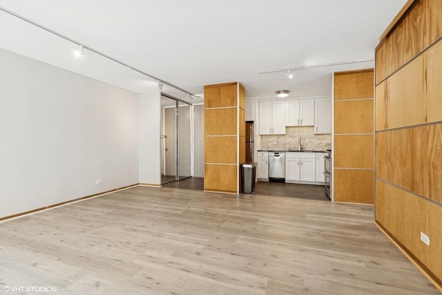 unfurnished living room with light wood-type flooring, track lighting, and a sink