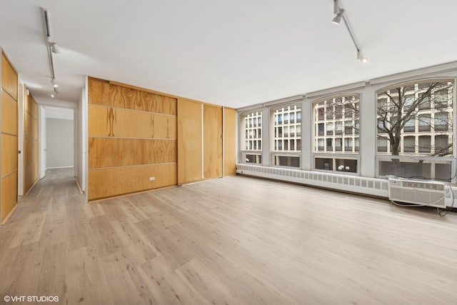 unfurnished room with baseboard heating, light wood-style flooring, and track lighting