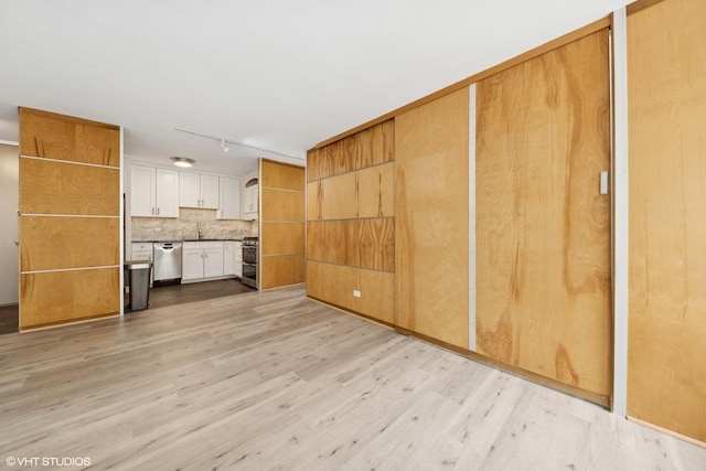 unfurnished living room with rail lighting, light wood-style flooring, and a sink