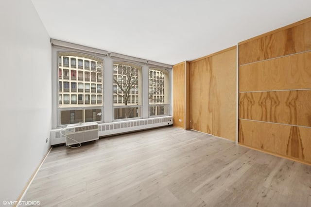 spare room featuring a wall unit AC and wood finished floors