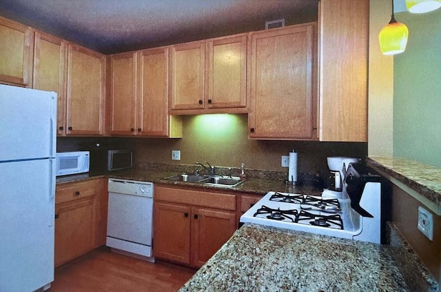 kitchen featuring light wood finished floors, white appliances, a sink, and pendant lighting