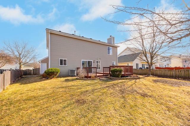 rear view of house featuring a fenced backyard, a chimney, a deck, cooling unit, and a yard