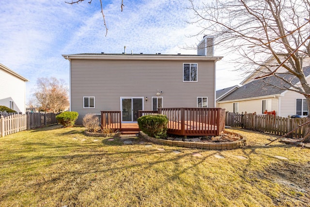 rear view of house with a fenced backyard, a chimney, a wooden deck, and a yard