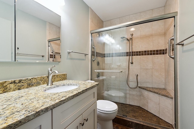 bathroom featuring a stall shower, toilet, and vanity