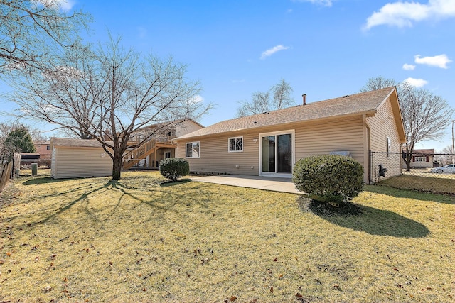 rear view of house featuring a patio, stairway, an outbuilding, fence, and a lawn