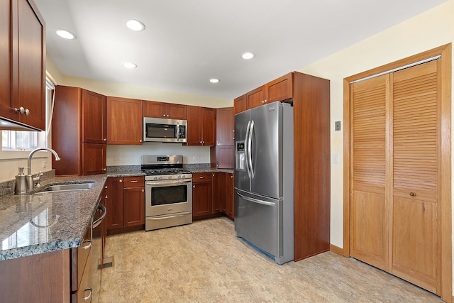 kitchen featuring a sink, stainless steel appliances, recessed lighting, and dark stone countertops