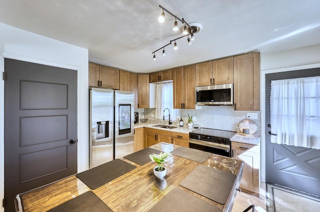 kitchen featuring a sink, stainless steel appliances, decorative backsplash, and light countertops